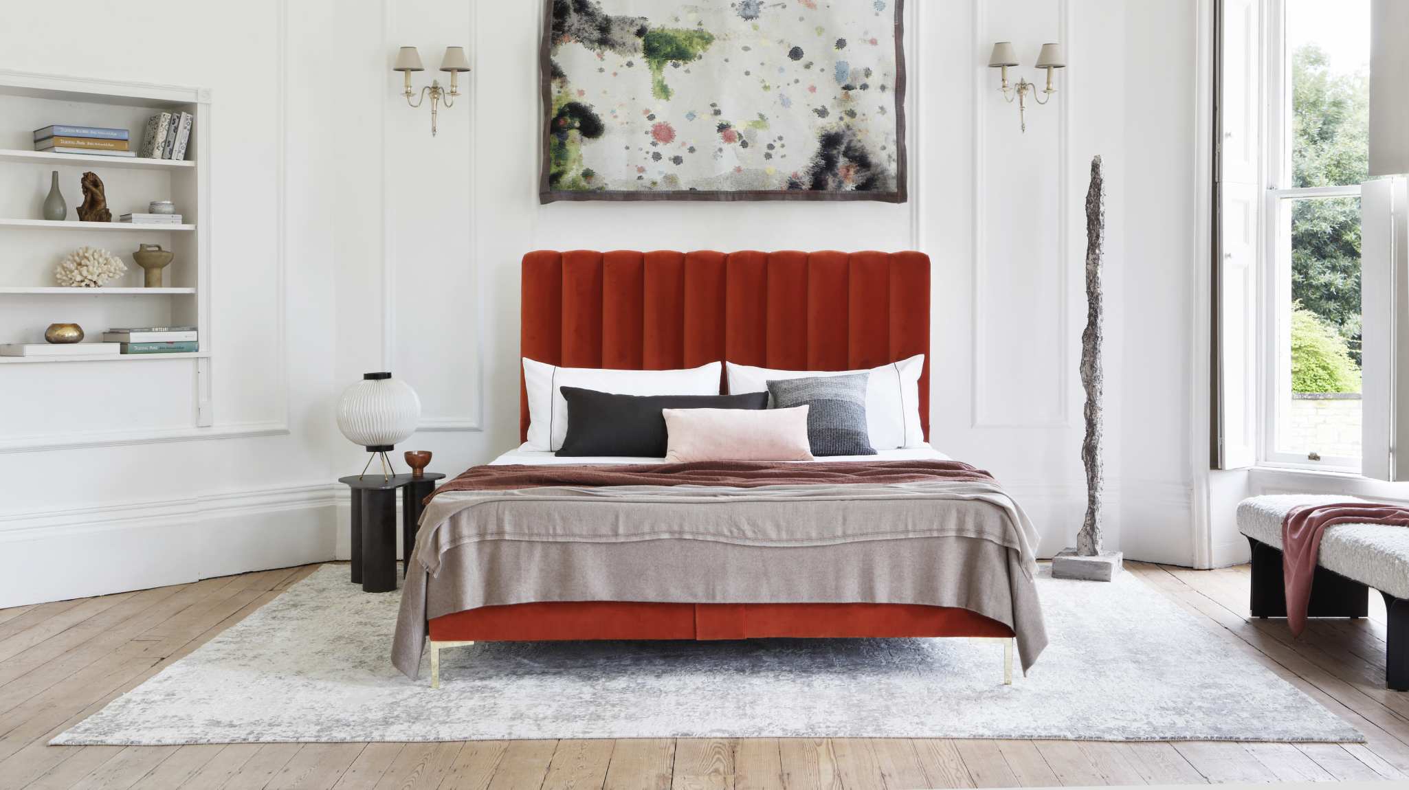 The Hudson design featuring a fluted bright orange headboard photographed against a stark white setting of a countryside mansion